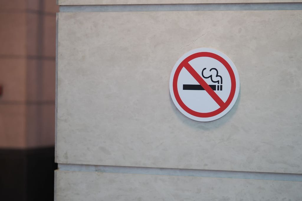 Tupakointi kielletty kyltti harmaalla talon betoniseinällä. 