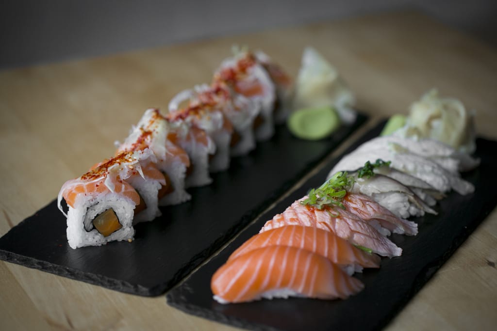 Sushiannoksia mustilla tarjoilualustoilla, nigiriä ja lohirullia.
