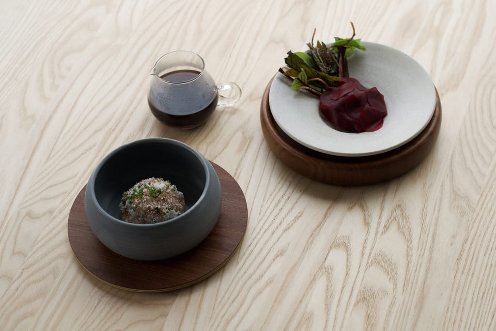 Ravintola Kaskiksen minimalistisesti aseteltuja gourmet-annoksia keraamisissa astioissa puupöydällä.