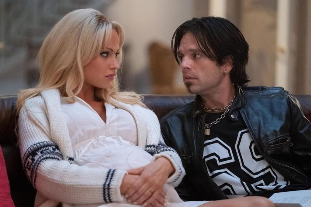 Vaaleahiuksinen nainen ja tummahiuksinen mies istuvat sohvalla vierekkäin ja katsovat toisiaan vakavina sisätiloissa.