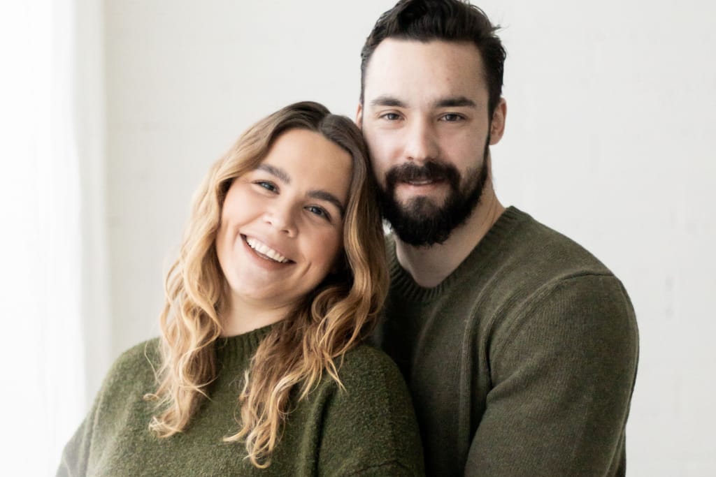 Eveliina Uosukainen ja Joni Rintala vaalealla taustalla vihreissä neuleissa hymyillen.