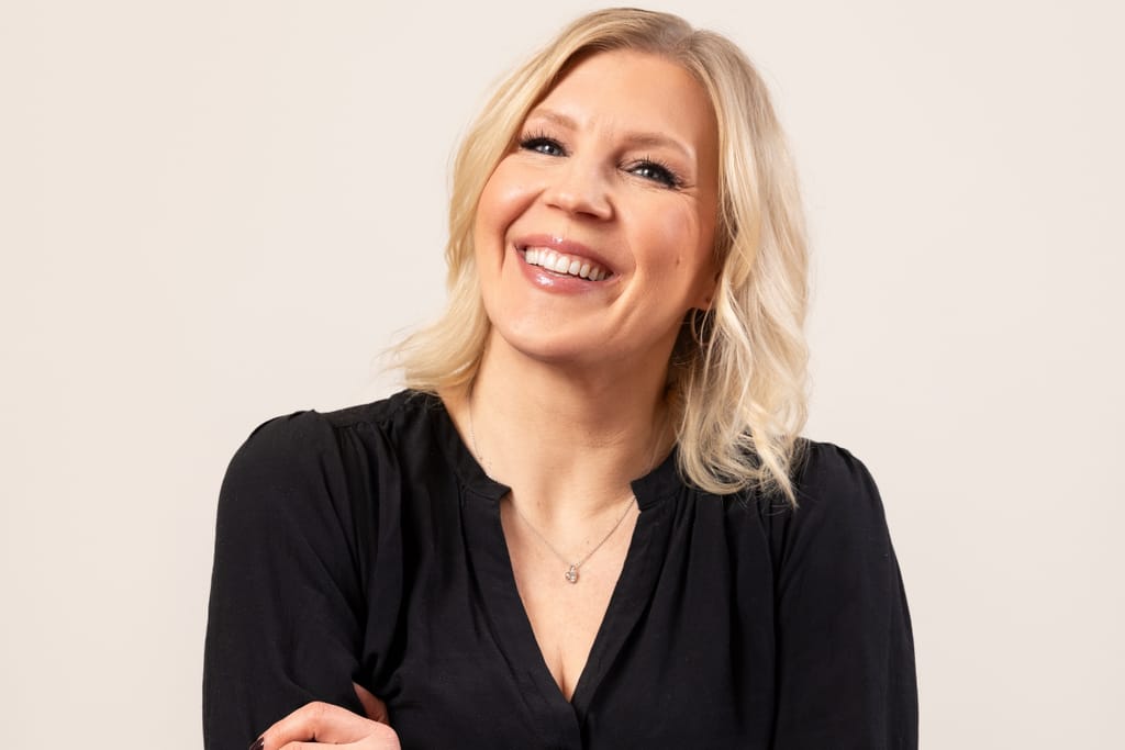 Vappu Pimiä vaalealla taustalla hymyillen.