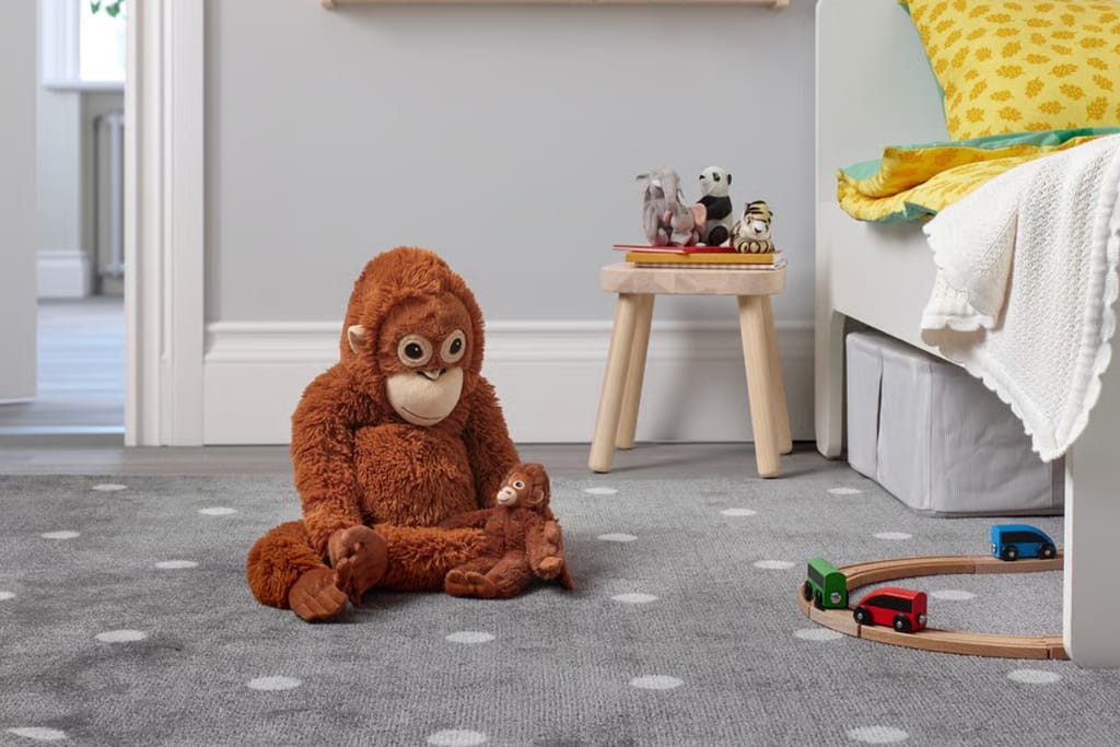 Ruskea pehmoapina istuu esillä huonekaluliikkeessä valkoista taustaa vasten.
