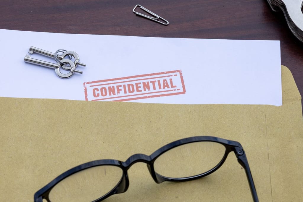 Kirjekuori ja paperi, jossa lukee “CONFIDENTIAL”, vieressä avaimet ja silmälasit.