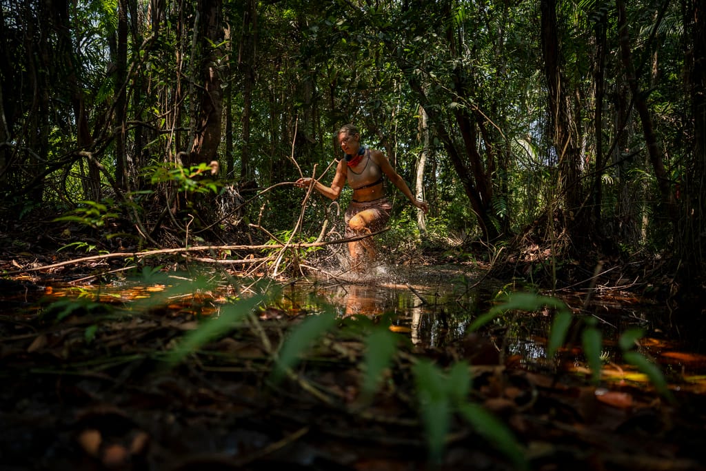 Kilpailija kahlaa viidakkopuroa pitkin tiheässä sademetsässä Selviytyjät-ohjelmassa.