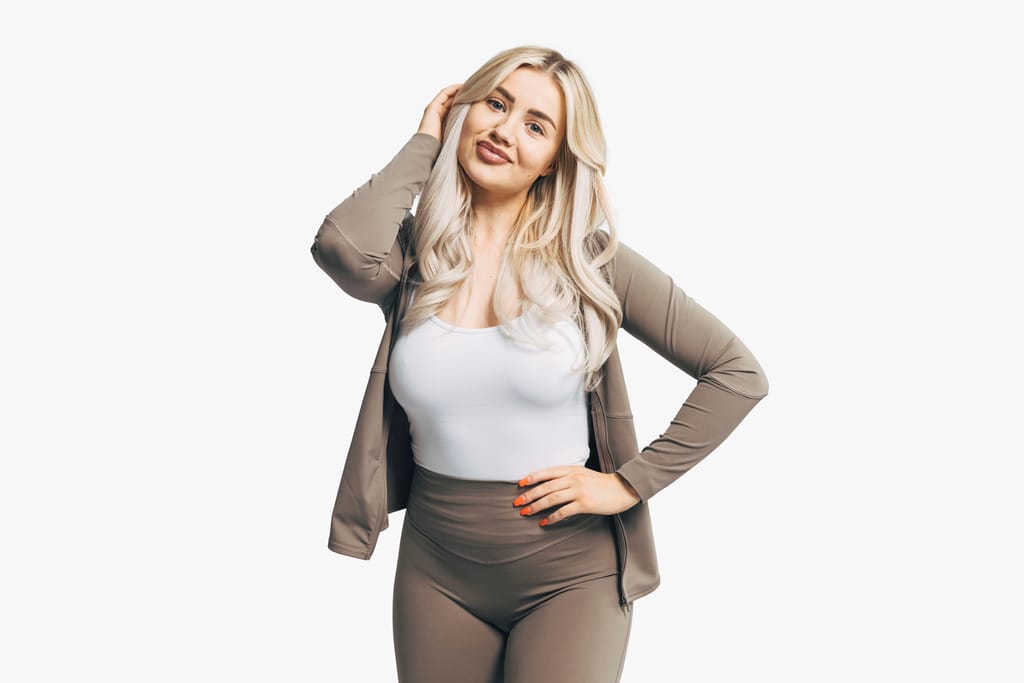 Sonja Aiello beigeissä treenivaatteissa valkoista taustaa vasten