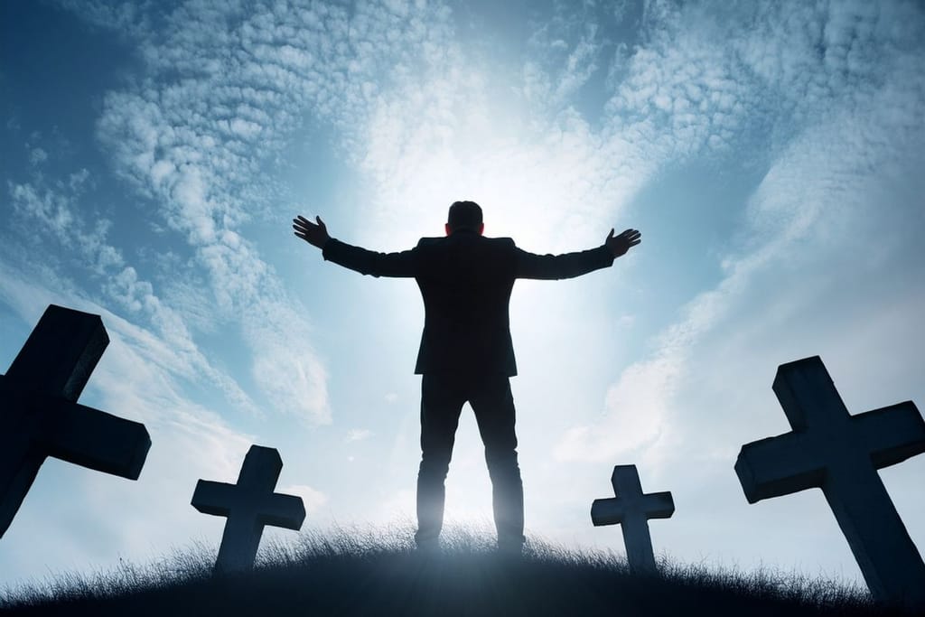 Mies seisoo hautausmaalla ristien keskellä kädet levällään vastavalossa, dramaattinen taivas taustalla