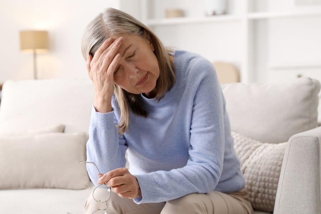 Väsynyt nainen pitelee päätään sohvalla – jatkuva uupumus voi liittyä matalaan ferritiiniin