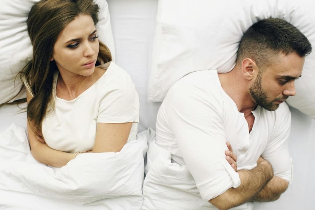 Pariskunta riidan jälkeen sängyssä selin toisiinsa – etäinen tunnelma
