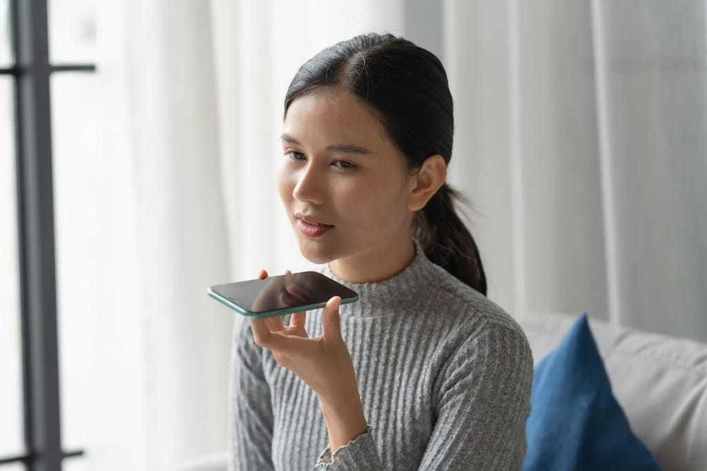 Nainen käyttää tekoälyä älypuhelimella kotona