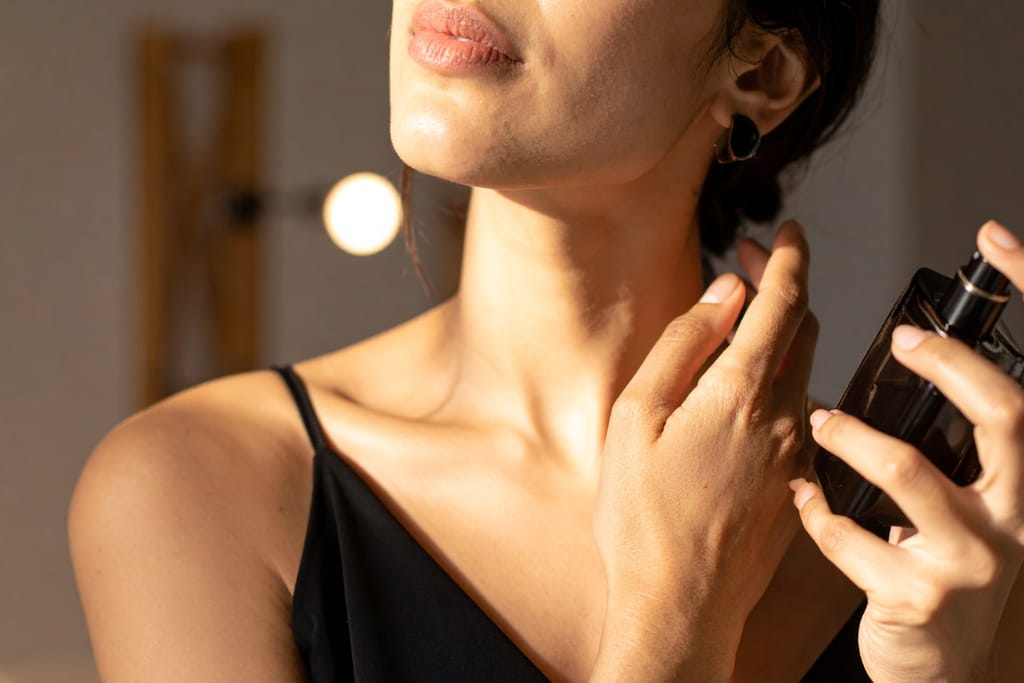 Nainen levittää hajuvettä kaulan iholleen pitäen hajustepulloa kädessään.