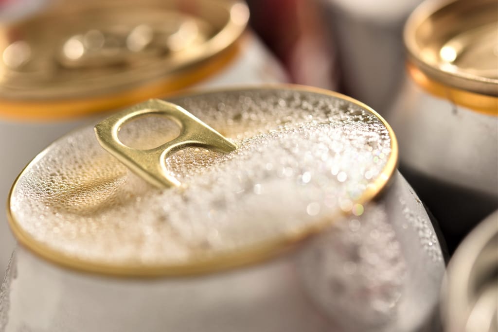 Lähikuva kylmästä juomatölkistä, jonka pinnalla on vesipisaroita ja avattu tölkinrengas.