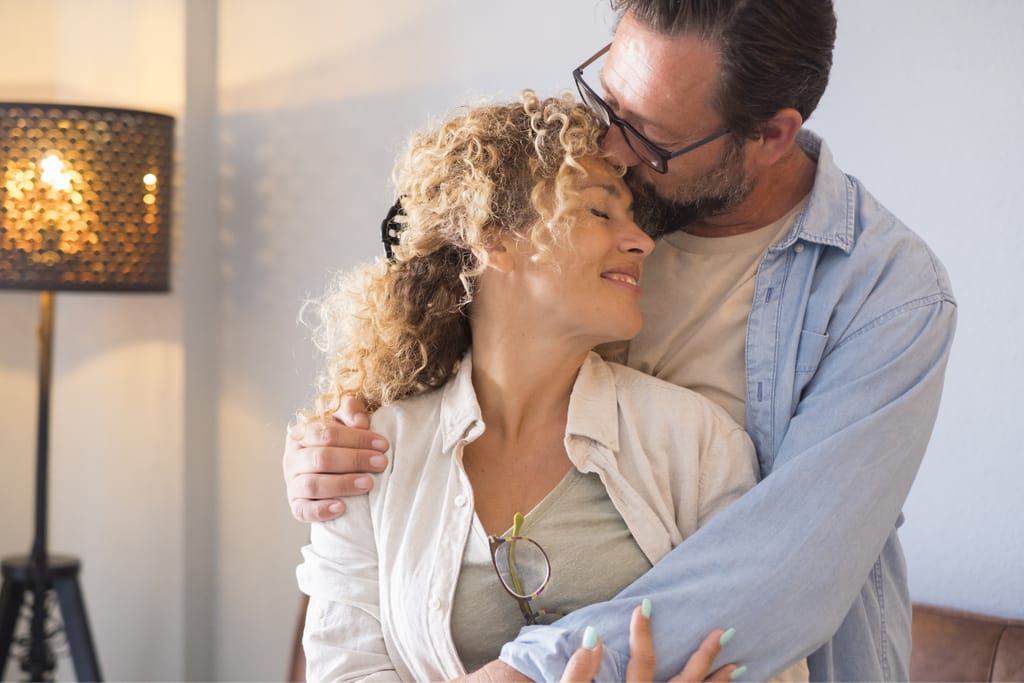 Mies halaa naista ja suutelee häntä hellästi otsalle.