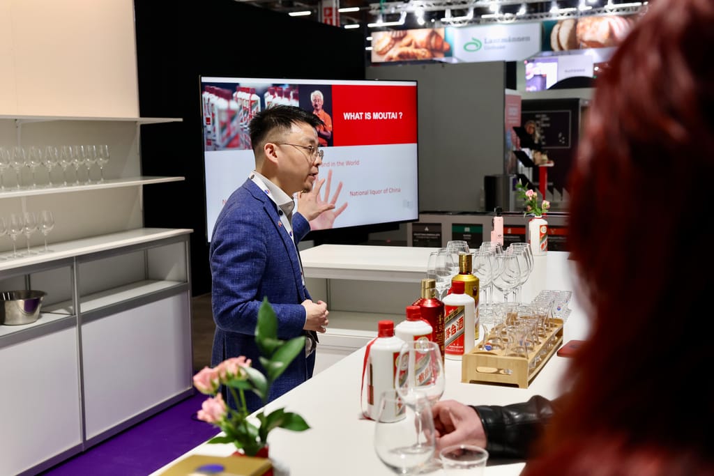 Mies pitää esitystä China Moutai -juomasta messuosastolla näytön edessä.