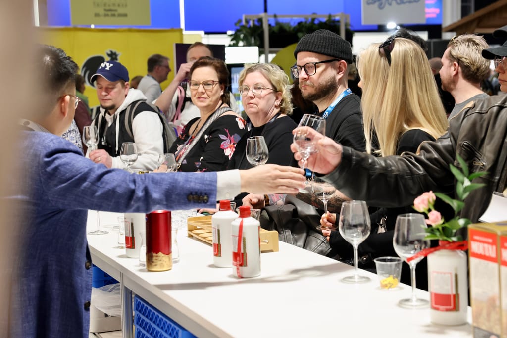 Mies pitää esitystä China Moutai -juomasta messuosastolla näytön edessä.