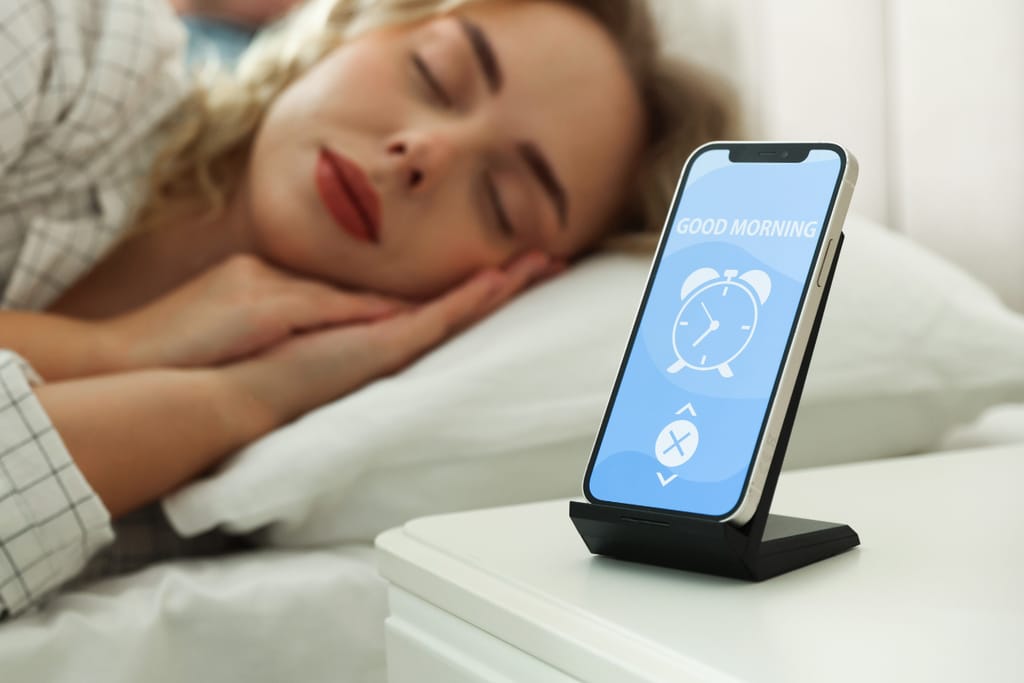 Nainen nukkuu sängyssä puhelin vieressä.
