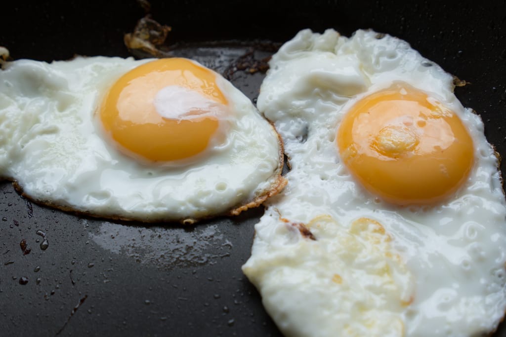 Kaksi paistettua kananmunaa pannulla.