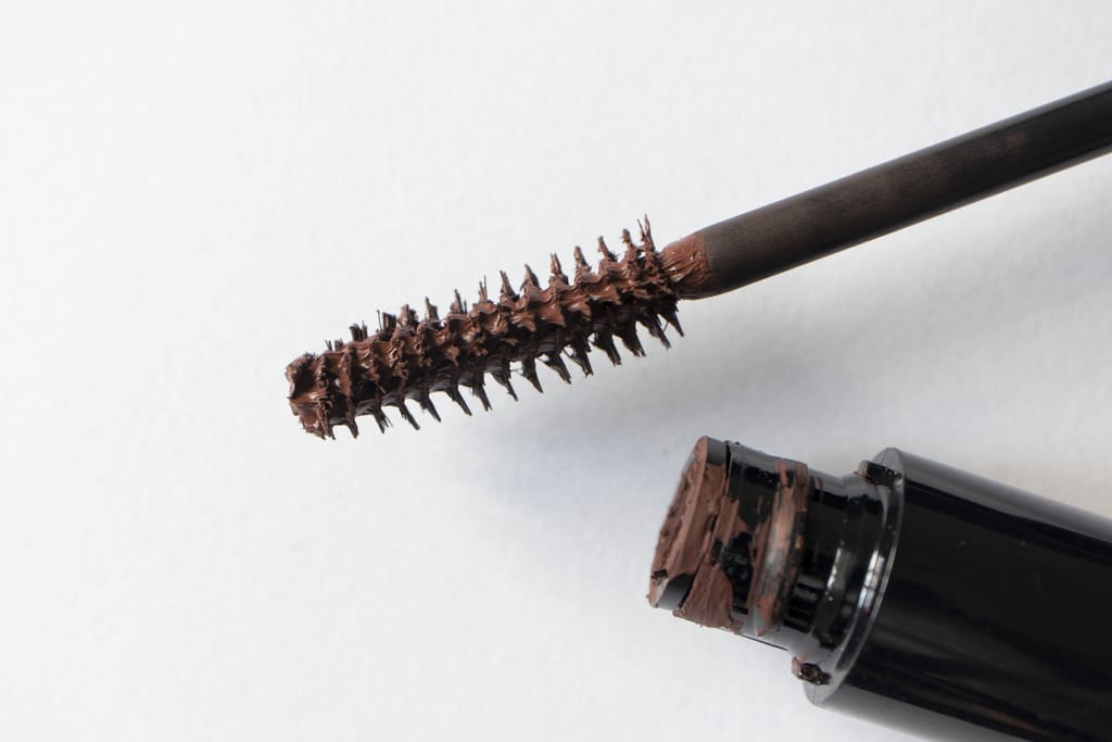 Ruskean ripsivärin harja ja avattu ripsiväripullo lähikuvassa.