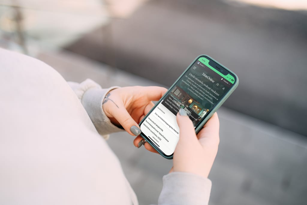 Henkilö selaa älypuhelimella ravintolahakusivustoa ja etsii ruokapaikkaa.