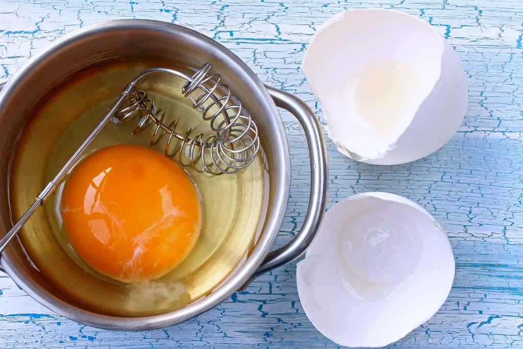 Raaka kananmuna rikottuna kattilaan. Vispilä mukana.