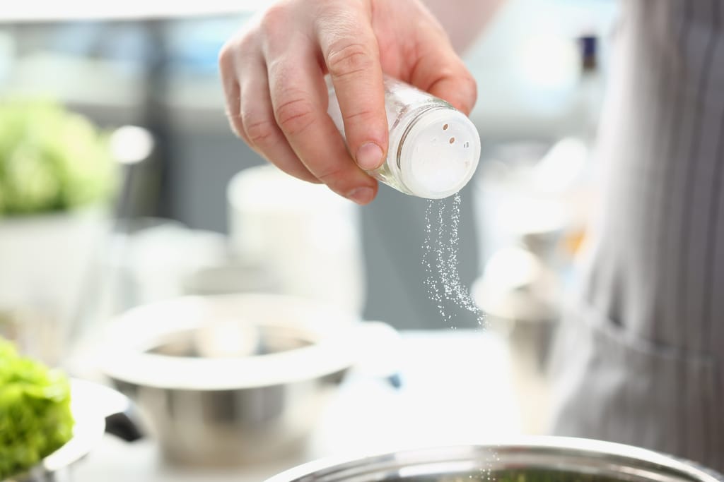 Henkilö laittaa ruokaa ja lisää suolaan kattilaan.