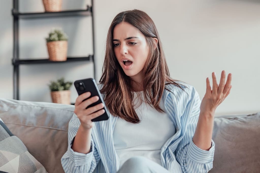 nainen turhautuneena selaa deittisovellusta puhelimella kotona