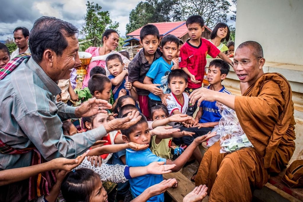 Munkki jakaa ruokaa lapsille ja perheille Aasiassa – hyväntekeväisyys ja avun tarve korostuvat globaalissa eriarvoisuudessa