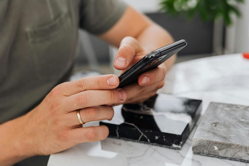 Kädet selaavat älypuhelinta – jatkuva skrollaaminen voi kuormittaa kehoa huomaamatta