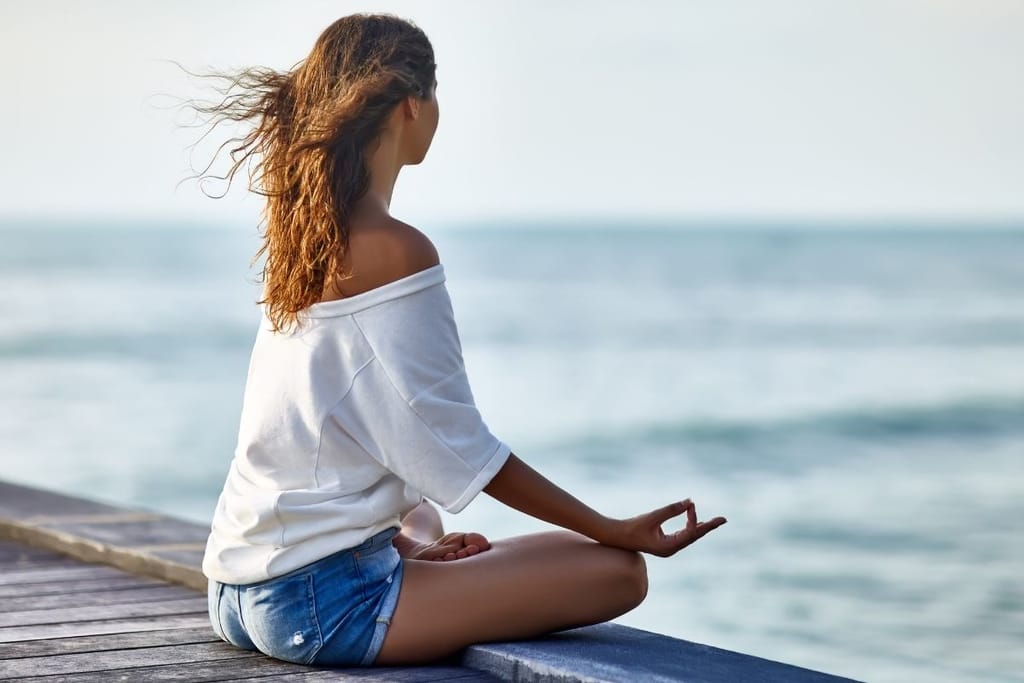 meditaatio meren rannalla mindfulness rentoutuminen keskittyminen rauha
