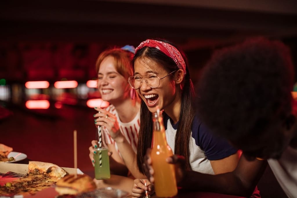 ystävät nauravat yhdessä ravintolassa musta huumori nauru iloinen tunnelma
