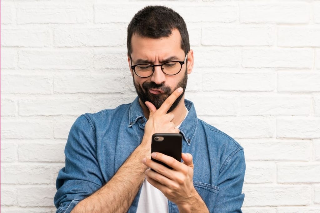 mies miettii vastausta puhelimeen ja epäröi viestin lähettämistä