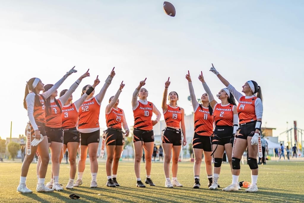 naisten urheilujoukkue kentällä juhlistaa peliä auringonlaskussa