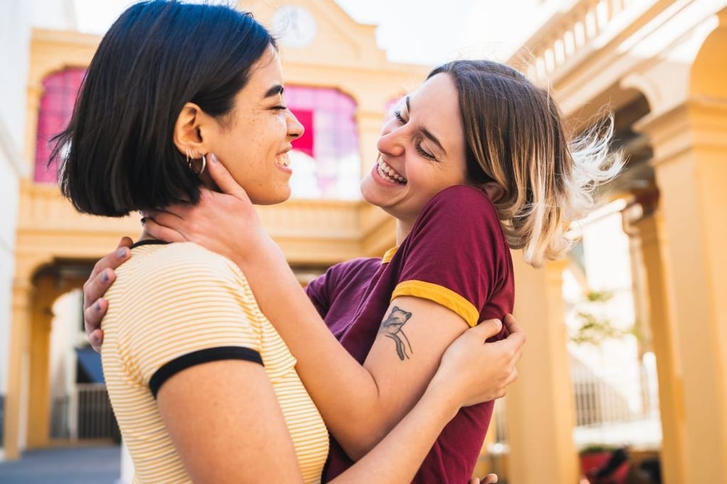 Kaksi naista halaa ja hymyilee läheisesti – nopea rakastuminen liittyy tunteiden voimakkuuteen