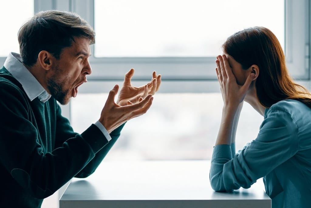 Pariskunta riitelee pöydän ääressä – mies huutaa ja nainen peittää kasvonsa käsillä