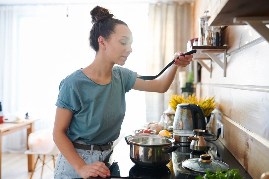 Nainen kokkaa keskittyneesti keittiössä – flow-tila tekee ruoanlaitosta sujuvaa
