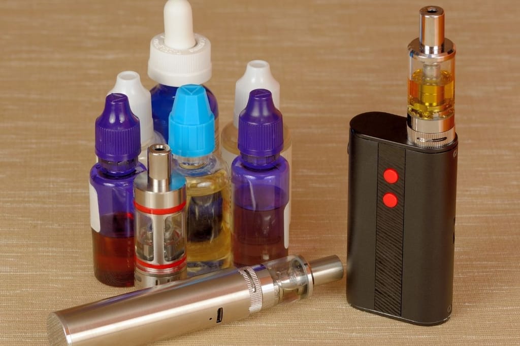 Sähkösavukelaite ja vape-nesteitä pöydällä – ladattavat vapet ja e-nesteet lähikuvassa