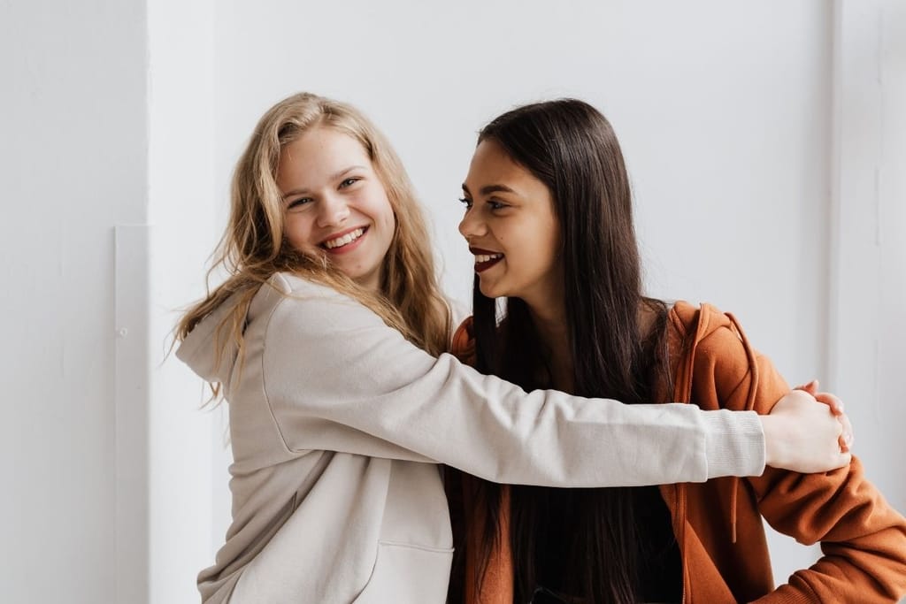 Kaksi naista halaa ja hymyilee – aito kiinnostus tekee ihmisestä rakastettavamman
