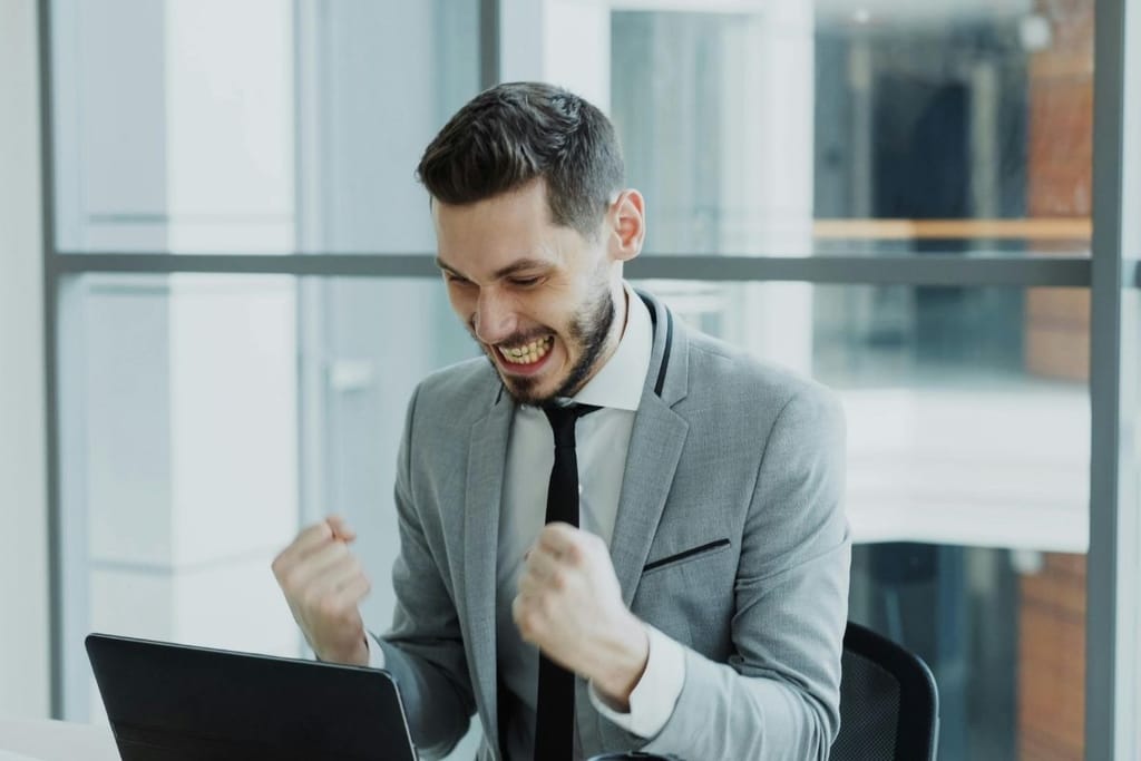 työelämä menestys ura eteneminen toimistossa mies juhlii läppärin äärellä