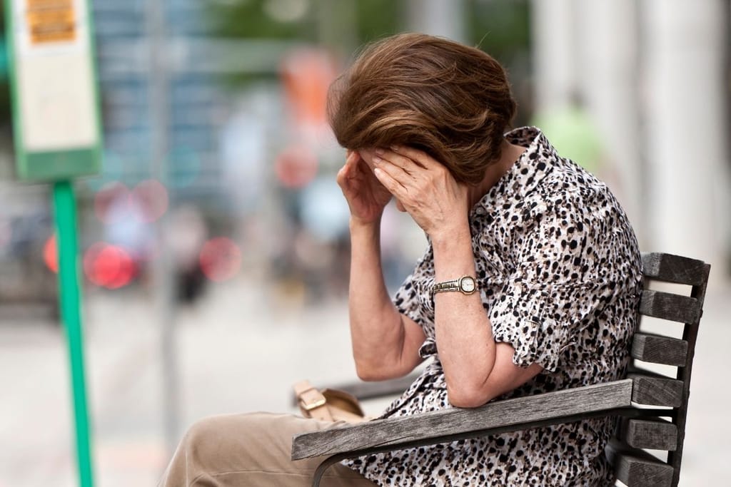 yksinäinen nainen istuu penkillä kaupungissa – yksinäisyys kaupungeissa kasvaa