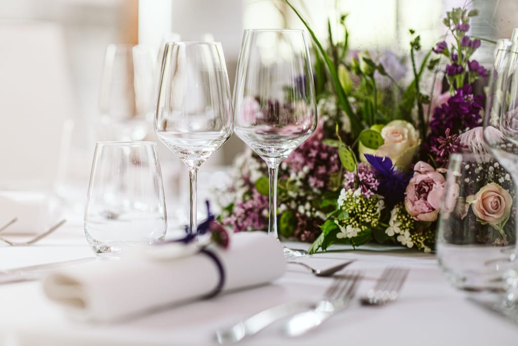 Ravintolapöytä, jossa kukkia ja kattaus.