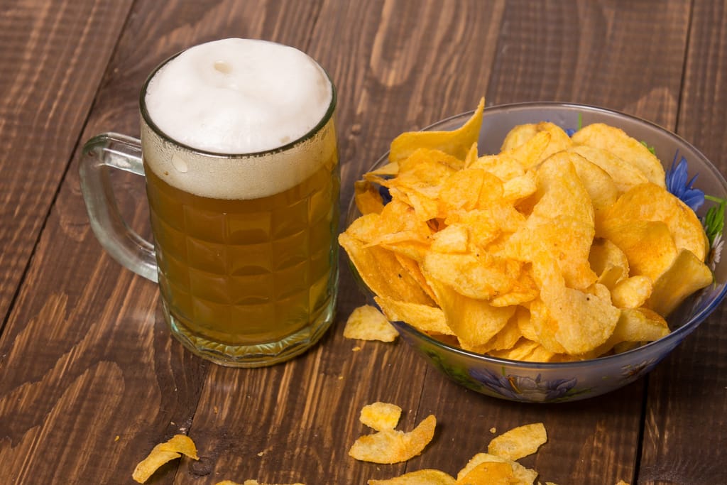 Kulhollinen sipsejä, jonka vieressä tuoppi olutta.