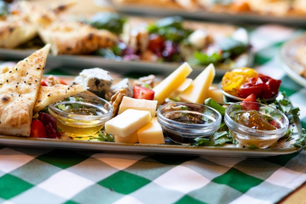 Antipasti-lautanen täynnä juustoja, leikkeleitä ja hilloja.