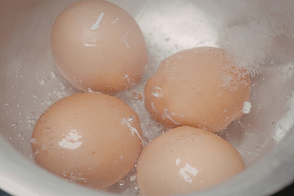 Kananmunia kiehumassa kattilassa vedessä.