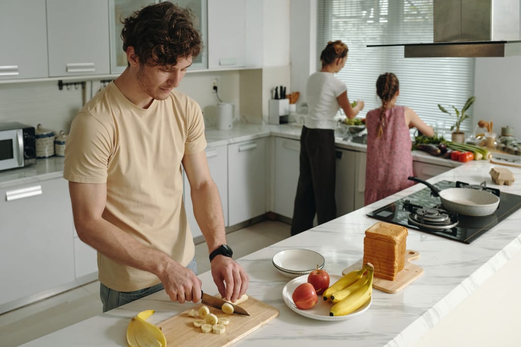 Perhe laittaa yhdessä ruokaa keittiössä.