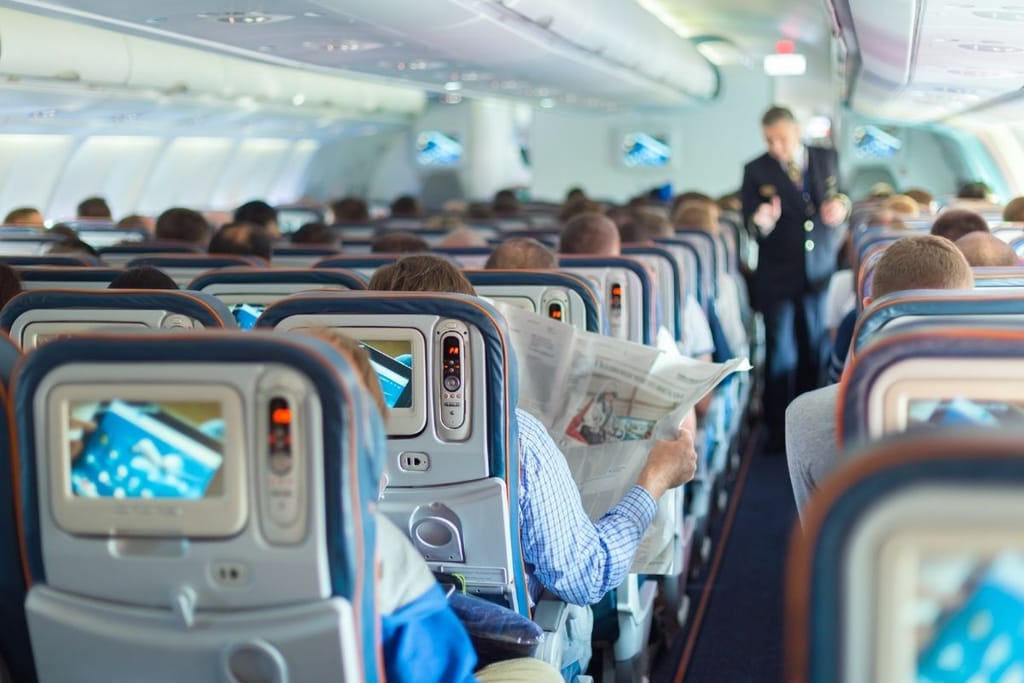 Lentokoneen matkustamo täynnä matkustajia – lentokoneetiketti ja käytöstavat lennolla puhuttavat