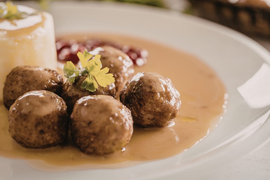 Lautasella lihapullia, kastiketta ja puolukkahilloa.