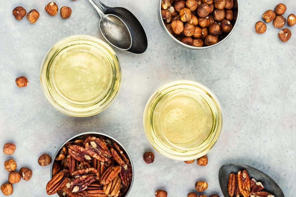 Pöydällä kulhoissa pähkinöitä ja kaksi viinilasia.