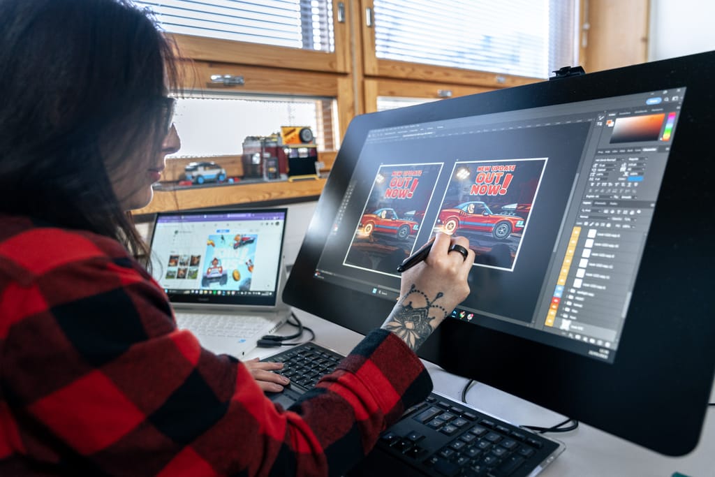 Graafinen suunnittelija työskentelee tietokoneella toimistossa luovassa työssä.