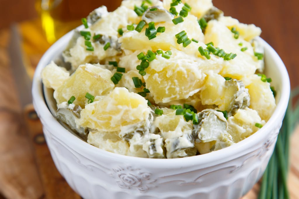 Kulhollinen perunasalaattia, jonka päällä ruohosipulia.