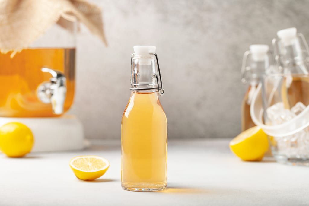 Pullollinen sitruunajuomaa pöydällä, vieressä sitruunoita.